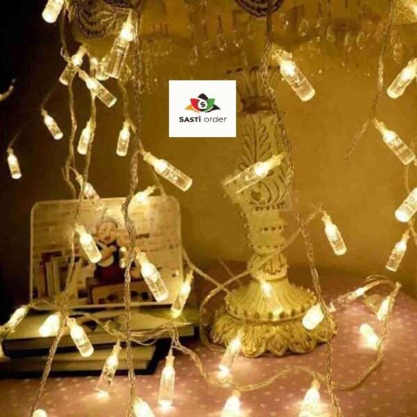 A string of 10 LED Bottle Shape Lights featuring mini bottle-shaped bulbs emitting a warm glow. The unique design adds a playful and stylish touch to any decor, ideal for indoor or outdoor use at parties, weddings, or home decorations. Battery-powered for easy portability and versatile placement.