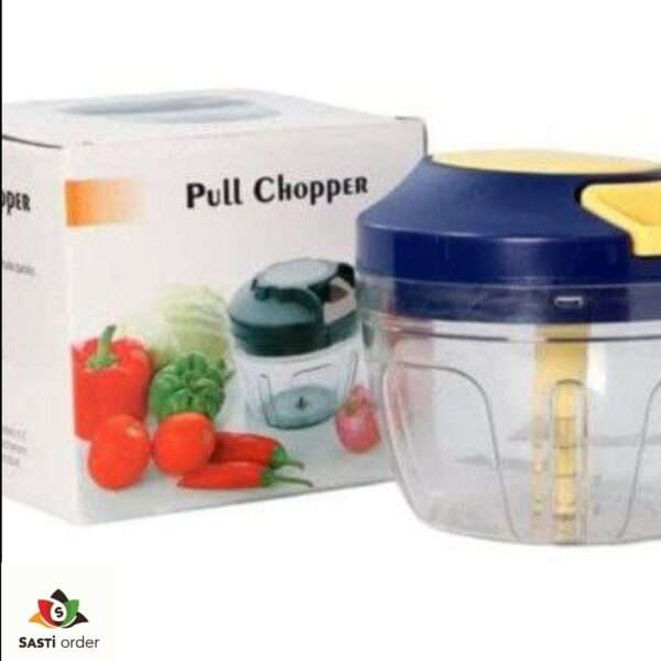 A Manual Vegetable Fruit Onion Chopper with a clear bowl, stainless steel blades, and a pull-cord mechanism, placed on a kitchen counter with chopped onions and vegetables nearby.